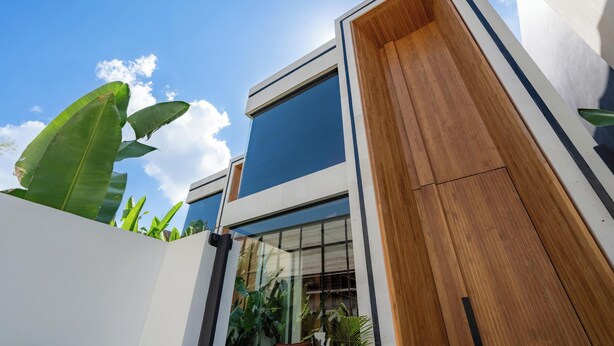 A modern building with large windows, a wooden facade, and lush green plants. - Art Villa by Betterplace (Ubud)