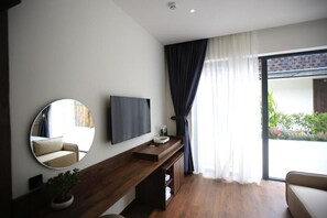 A modern room with a wooden console table, a flat-screen TV, a round mirror, a potted plant, and a sliding glass door leading to an outdoor area. - DD Hospitality - Mi Amor Da Lat (Da Lat)