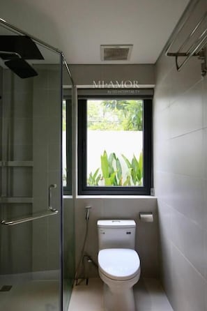 A compact bathroom with a toilet, a window, and a shower area. - DD Hospitality - Mi Amor Da Lat (Da Lat)