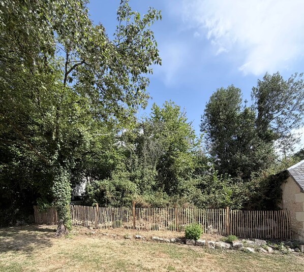 A fenced yard with trees and a stone building.