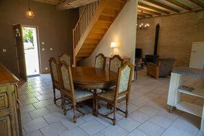 Ein Essbereich mit Holztisch und Stühlen, einer Treppe, einem Fernseher und einem Kühlschrank.