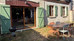 Una casa con un patio, una parrilla y una mesa con sillas.