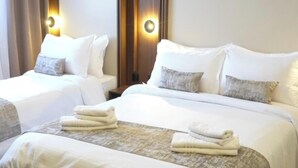 A hotel room with two beds, a wooden headboard, a nightstand, and a view of the city. - Cozzy Inn (Oran)