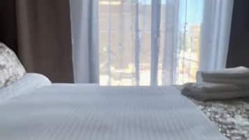 Habitación de hotel con cama, cortinas y vistas a edificios.