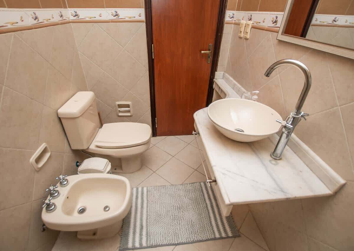 A bathroom with a toilet, bidet, sink, and mirror.