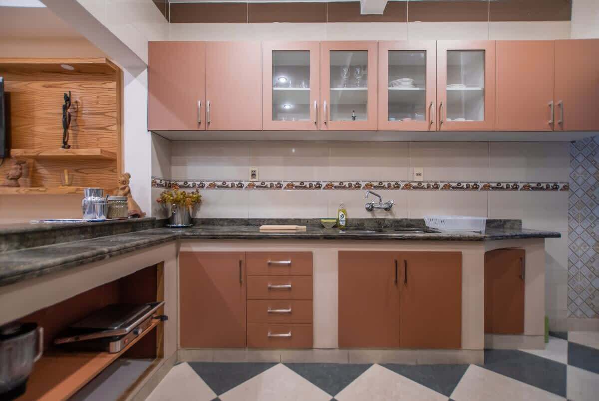 A kitchen with wooden cabinets, a marble countertop, and a tiled backsplash.