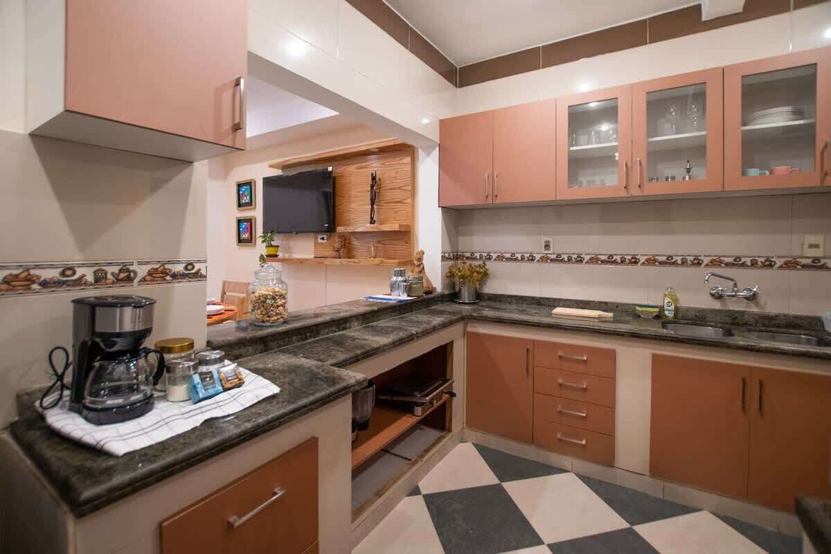 Cozinha com cafeteira, potes e uma televisão na parede.