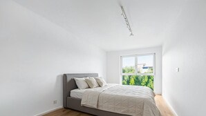 Ein Schlafzimmer mit einem Bett, einem Fenster und Blick auf Grünfläche draußen.