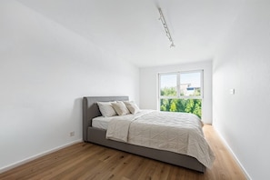 Ein Schlafzimmer mit einem Bett, einem Fenster und Blick auf Grünfläche draußen.