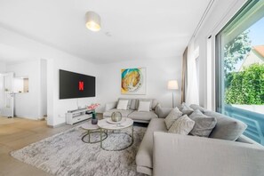 A modern living room with a grey sofa, a flat-screen TV, a coffee table, and a painting on the wall. - Modern Luxury Villa, 5 Bedrooms, Alte Donau (Wien)