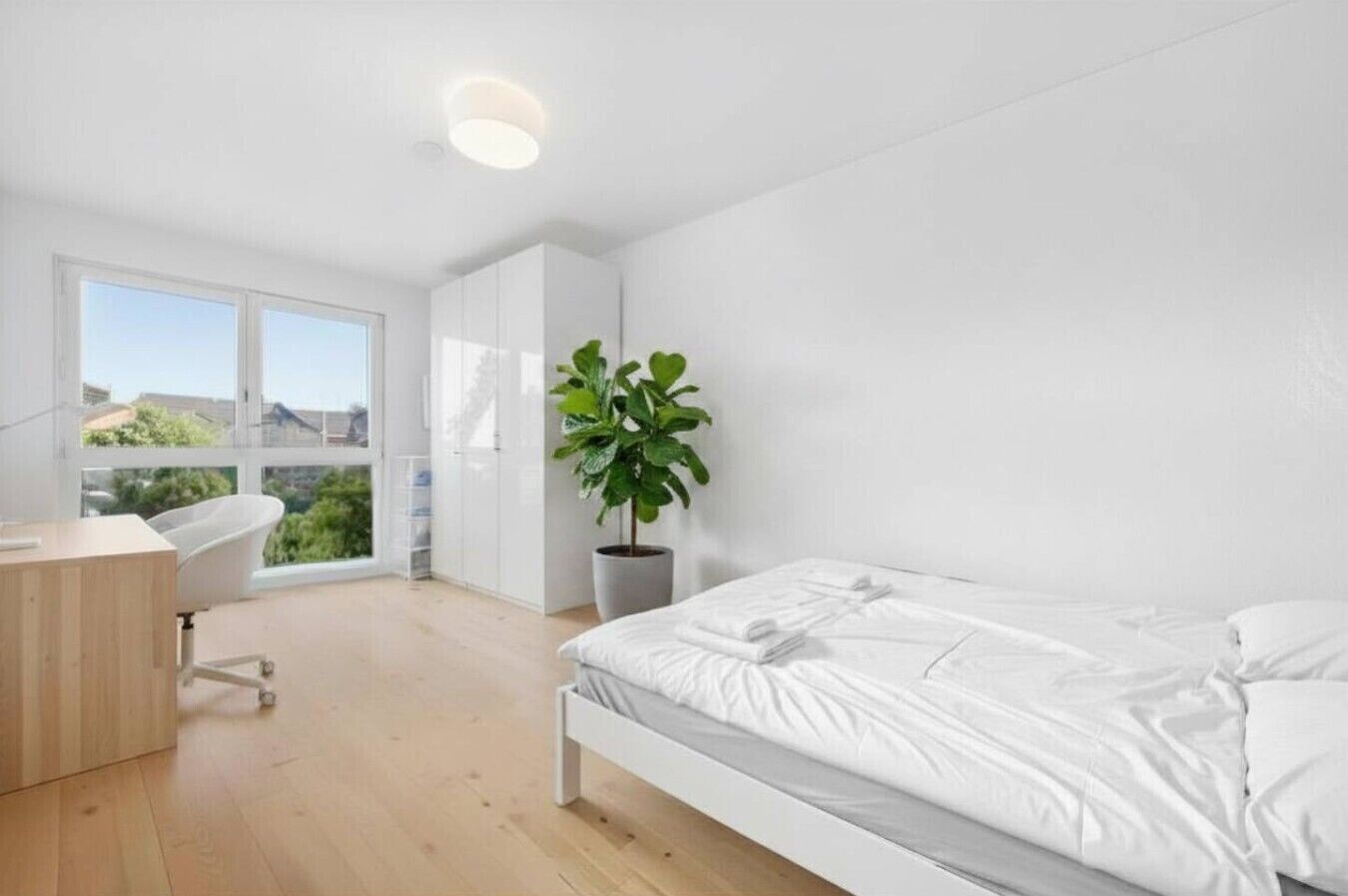 Ein modernes Schlafzimmer mit einem Bett, einem Schreibtisch und einem großen Fenster.