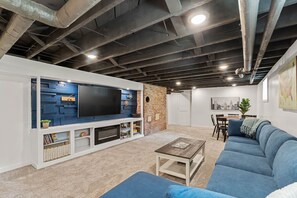 Ein Wohnzimmer mit Flachbildfernseher, einer Ziegelwand, einer Couch und einem Couchtisch.