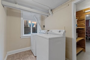 Ein Waschraum mit zwei weißen Waschmaschinen, einem Fenster und einer Holzeinrichtung.
