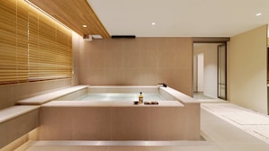 A modern bathroom with a large bathtub, wooden blinds, and a small tray with items. - Anook Hotel Busan Gwangalli (Busan)