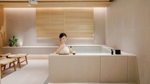 A modern bathroom with a bathtub, a sink, and a window with blinds. - Anook Hotel Busan Gwangalli (Busan)