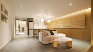A modern living room with a sofa, a coffee table, and a dining area in the background. - Anook Hotel Busan Gwangalli (Busan)
