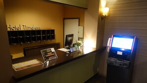 Un mostrador de recepción de hotel con un quiosco digital, una barra de recepción y una pantalla en la pared que muestra zapatos.