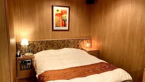 Una habitación de hotel con una cama grande, una mesita de noche con una lámpara, un teléfono y un cuadro en la pared.