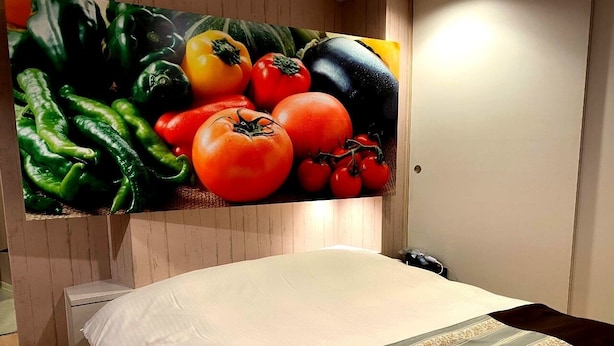 A bedroom with a bed, a nightstand, and a wall-mounted TV displaying vegetables. - HOTEL TIMELESS - Adults Only (Akashi)