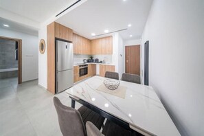 Une cuisine moderne avec des meubles en bois, un réfrigérateur en acier inoxydable et une table à manger en marbre.