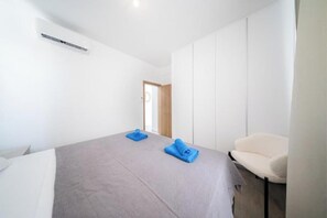 A hotel room with a bed, a chair, and a door. - Serene Gardens 2BR w/ Pool (Livadia Larnakas)