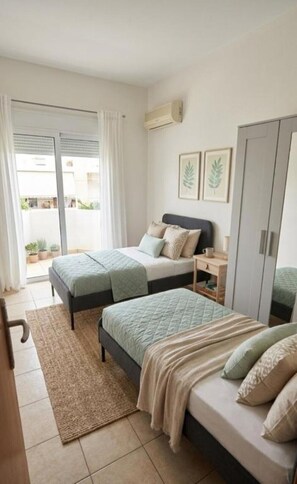 A bedroom with two beds, a small bedside table, a wardrobe, and a sliding glass door leading to an outdoor area. - Η Ιδανική Απόδραση στη Ρόδο Πολυτελής Βίλα Κοντά στη Θάλασσα με ιδιωτική πισίνα (Lardos Rhodes)