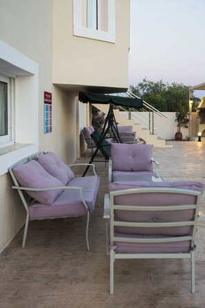 An outdoor seating area with two lounge chairs and a table, a staircase, and a wall with a sign.