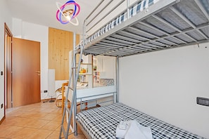 Ein Schlafsaalzimmer mit Etagenbetten, einer Holztür, einem kleinen Schreibtisch und einem Spiegel.