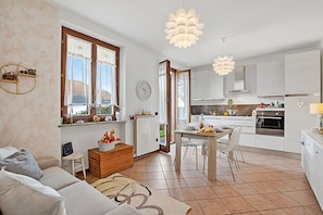 A modern kitchen with white cabinets, a dining area with a table and chairs, and a living room with a sofa and a coffee table. - Alba Rosa Apartment - 2 Bed, 2 Bath (Taino)