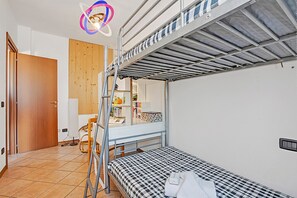 A bunk bed room with a wooden door, a small desk, and a mirror. - Alba Rosa Apartment - 2 Bed, 2 Bath (Taino)