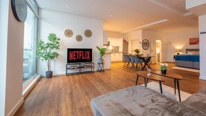 Una sala de estar moderna con un televisor de pantalla plana, un comedor y un sofá.