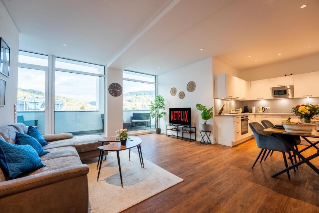 A modern living space with a sofa, coffee table, and a kitchen area with a dining table.