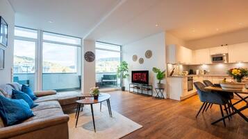 A modern living space with a sofa, coffee table, and a kitchen area with a dining table.
