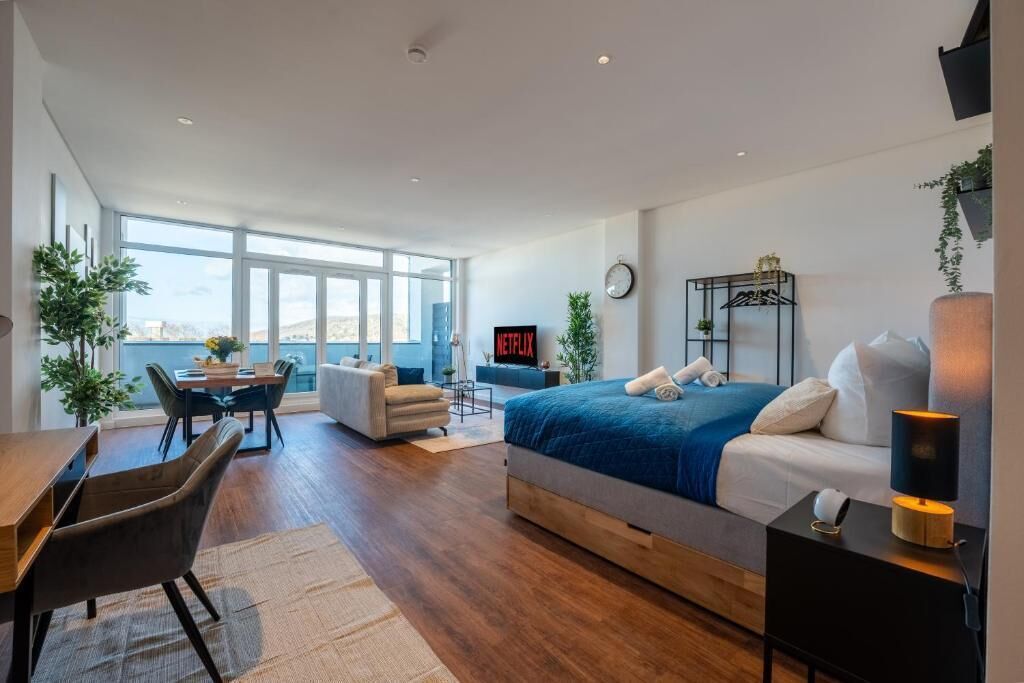 Une chambre d’hôtel moderne équipée d’un grand lit, d’un bureau, d’une chaise et d’un téléviseur.