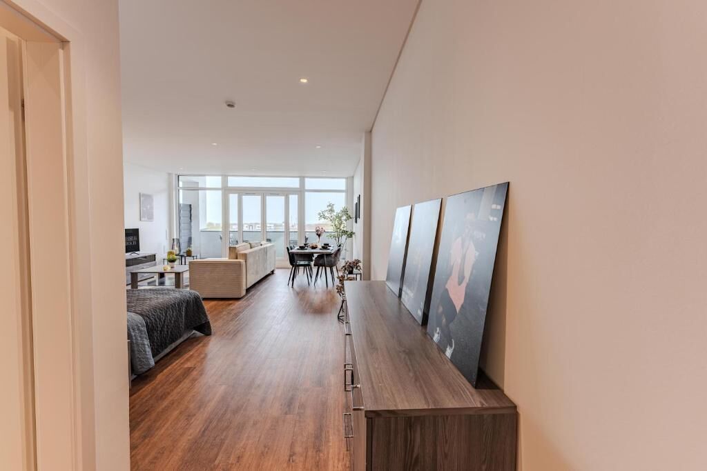 A modern interior with a long wooden bench, a dining area with a table and chairs, and a large window providing natural light.