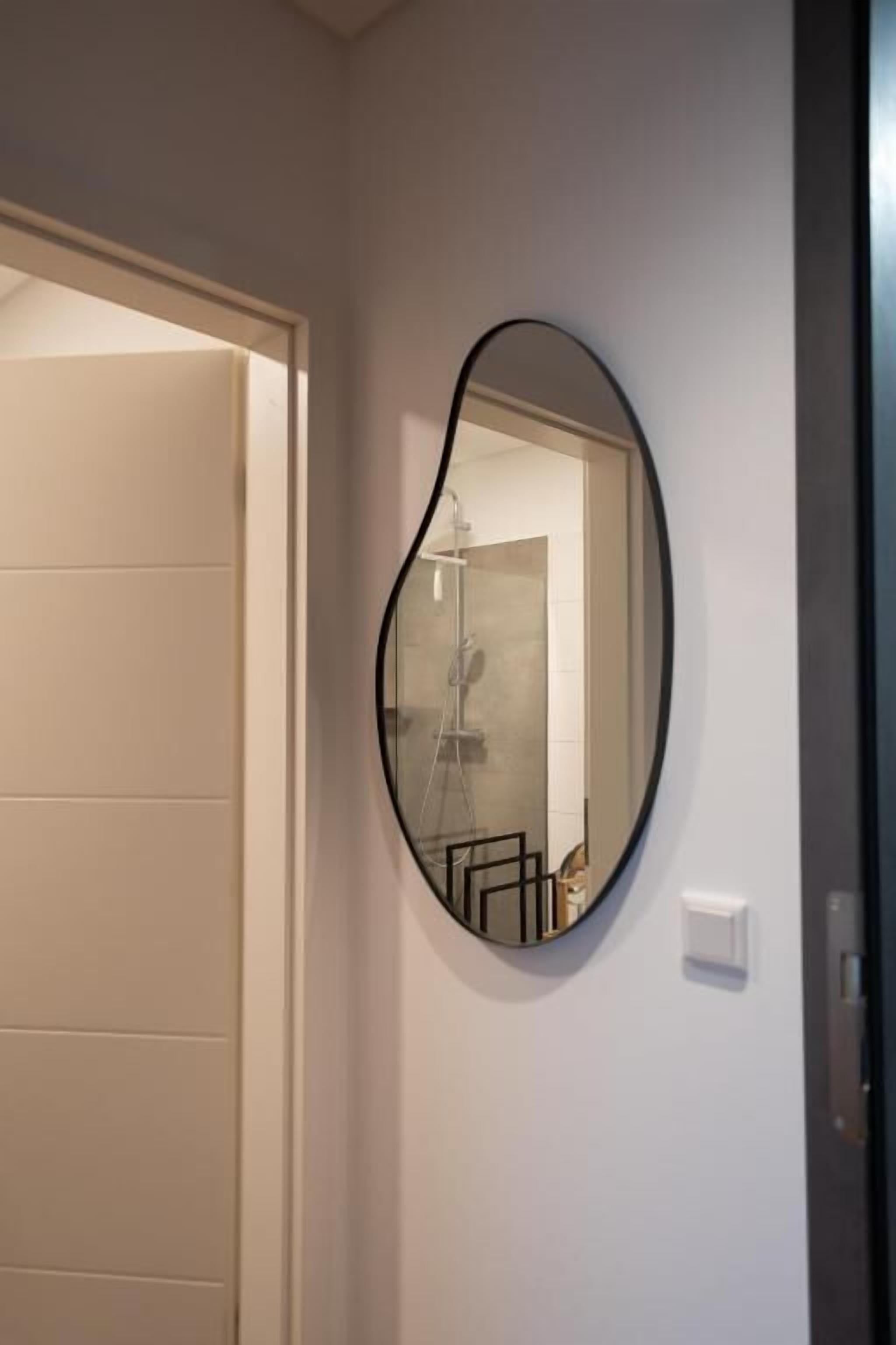 A bathroom with a large mirror, a shower, and a door.