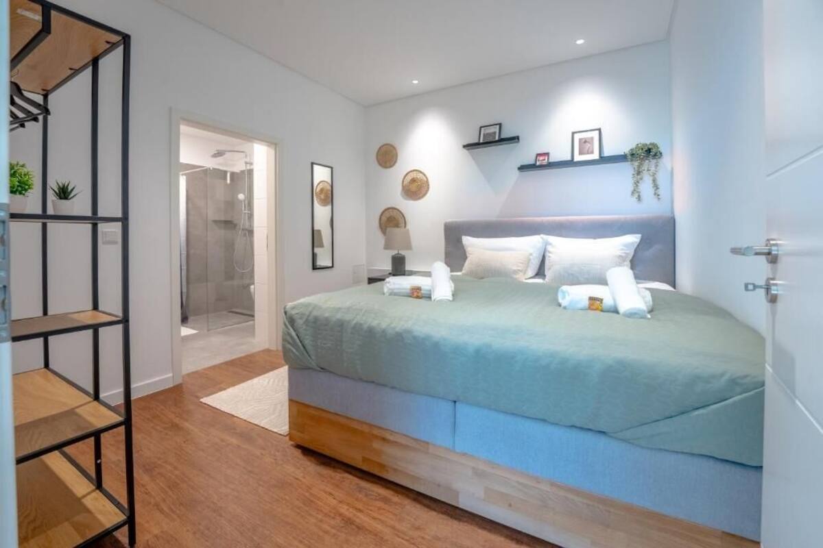 A modern bedroom with a bed, bedside table, and a glass shower enclosure.