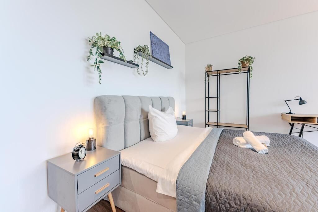 Een moderne slaapkamer met een bed, nachtkastje, wandplanken met planten.
