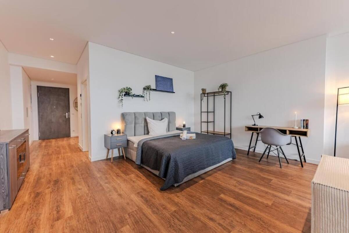 A bedroom with a bed, bedside tables, a desk, and a chair.