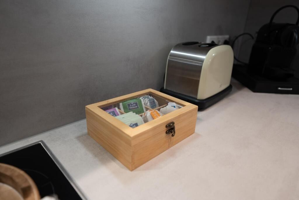 A wooden box with a latch on a countertop, next to a toaster and a coffee maker.