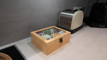 A wooden box with a latch on a countertop, next to a toaster and a coffee maker.