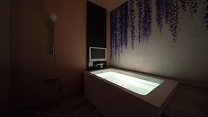 Un baño moderno con una bañera grande, ducha y un televisor de pared.