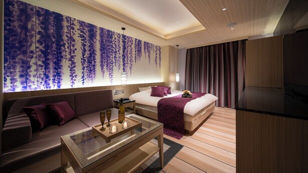 Una habitación de hotel moderna con cama, sofá y una mesa de centro de vidrio.