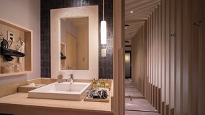 Un baño moderno con un espejo grande, un lavamanos y artículos de aseo.
