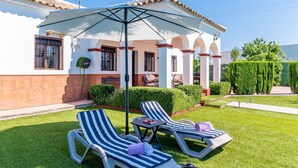 A patio with two lounge chairs, a table, and a large umbrella. - El Azahar Holiday Home (La Puebla de Cazalla)