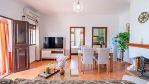 A living room with a TV, dining area, and kitchen in the background. - El Azahar Holiday Home (La Puebla de Cazalla)