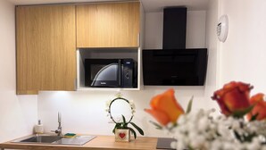 Eine moderne Küche mit Holzausstattung, einer Mikrowelle, einem Spülbecken und einer kleinen Pflanze auf der Arbeitsplatte.
