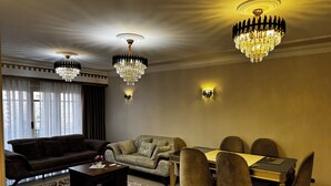 A living room with a sofa, a coffee table, a dining table with chairs, and two chandeliers. - Stylish 3-bedroom apartment with AC in Nasr city, Near to Cairo Airport (Nasr City)