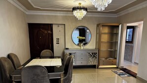 A dining area with a table, chairs, a chandelier, a mirror, and a cabinet. - Stylish 3-bedroom apartment with AC in Nasr city, Near to Cairo Airport (Nasr City)