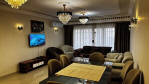 A modern living room with a dining table, multiple sofas, and two chandeliers. - Stylish 3-bedroom apartment with AC in Nasr city, Near to Cairo Airport (Nasr City)